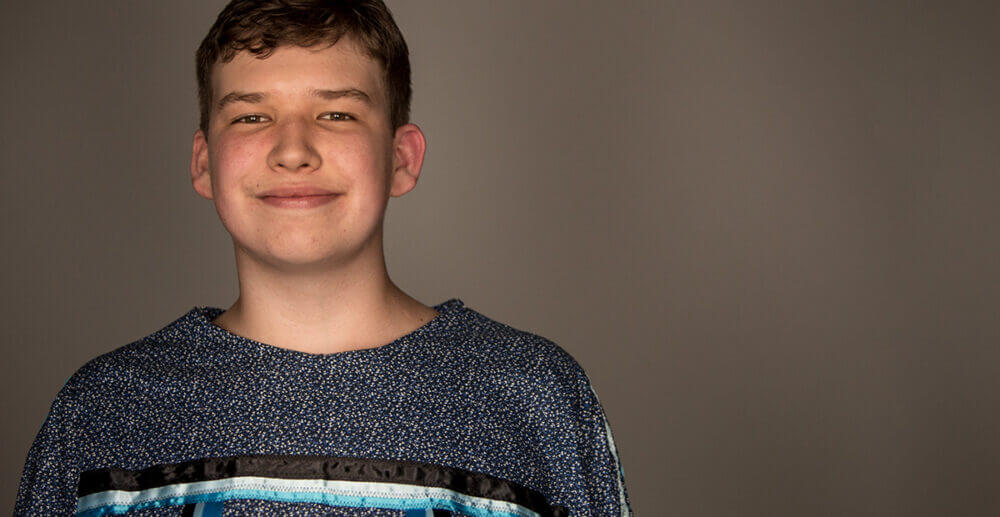 Aleks Kukk smiling at camera against a solid dark gray background